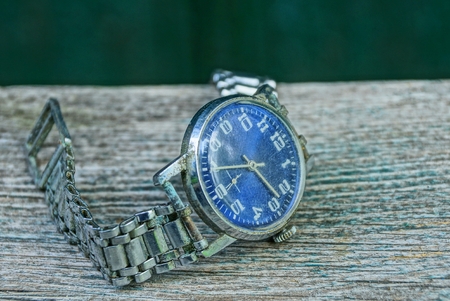 one blue old shabby watch with a metal strap on a gray tableの写真素材