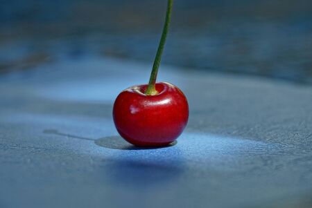 red ripe cherry berry lies on a blue tableの写真素材