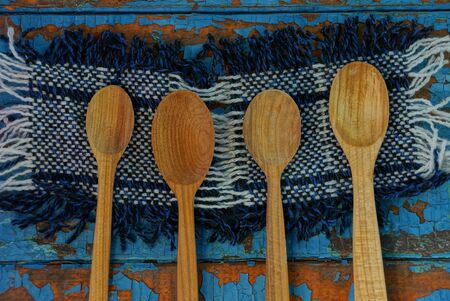 brown wooden spoons lie on a woolen napkin on a blue tableの写真素材