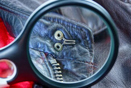 black leather magnifier magnifies metal rivets and zip on brown leather clothesの写真素材