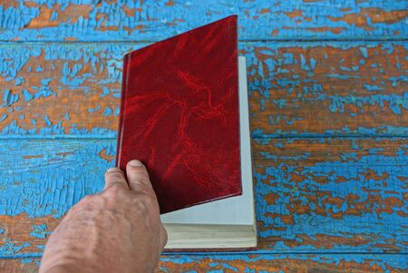 hand opens red old book