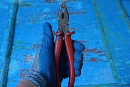 glove holds red old pliers