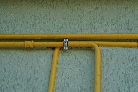 yellow metal gas pipes on a gray wall of a buildingの写真素材