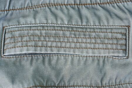 gray fabric texture of a piece of cotton clothing with a seam and pocket