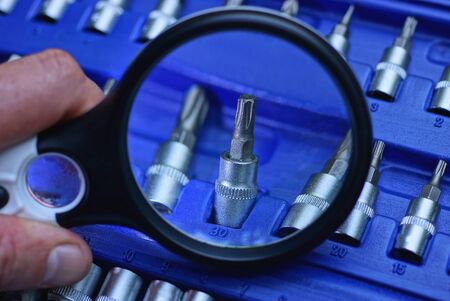 black magnifier enlarges screwdriver bit in blue plastic box