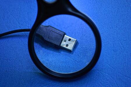 magnifier enlarges black usb cord with plug on blue table