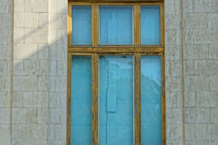 large old blue window with a brown frame on the gray stone wall of the house