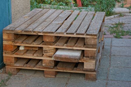 brown wooden pallets stand on the street against the wall