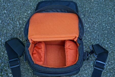 black red camera bag lies on gray asphalt