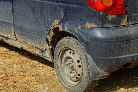 old blue car with a rusty wing and a gray wheel
