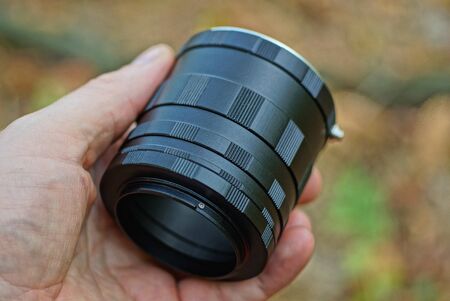 fingers holding a set of black metal macro lenses on the street