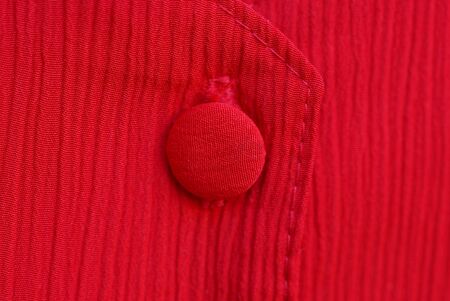 red fabric texture with a large single button on clothesの写真素材