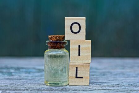 the word oil from wooden letters and a glass small bottle on a gray table