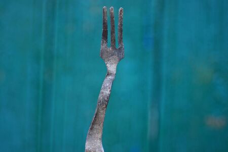 dirty old and bent aluminum fork on a green backgroundの写真素材