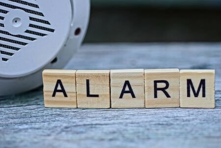 word alarm made of wooden letters and a plastic annunciator on a gray tableの写真素材