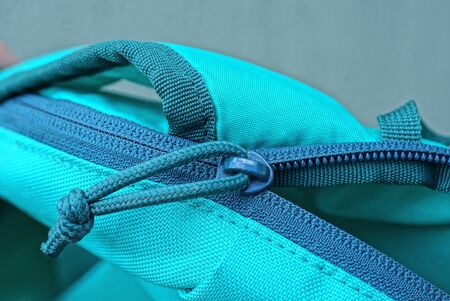 green zip and closure on the fabric of an open backpack