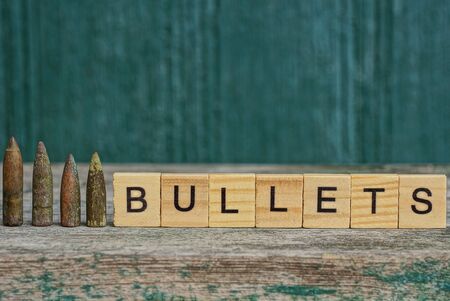 word made of wooden letters and a row of old bullets on the tableの写真素材