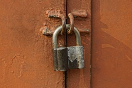 one gray big padlock on a brown iron wallの写真素材