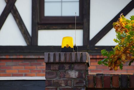 one yellow signal light hanging on a brown brick fence