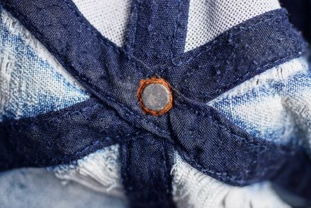 rusty gray metal rivet on blue fabric with seams and stripes
