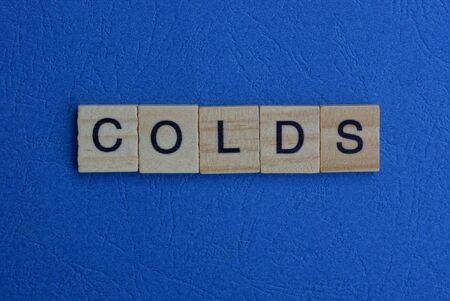 word colds of brown wooden letters lies on a blue tableの写真素材