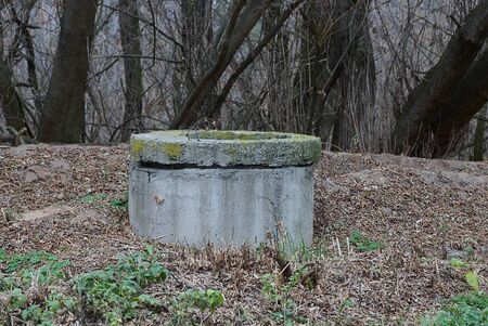 old gray concrete sewer stands in dry grass on nature