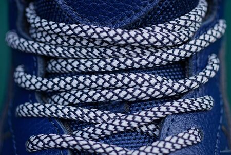 white lace on the blue leather of the shoe with a seam