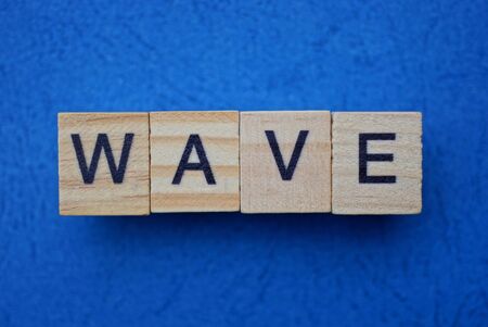 word wave made from gray wooden letters lies on a blue tableの写真素材