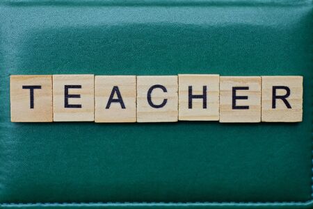 word teacher made from brown wooden letters lies on a green table