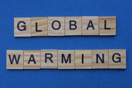 phrase global warming made from gray wooden letters lies on a blue tableの写真素材