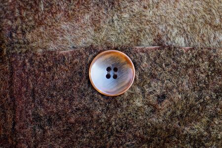 one brown button on a piece of woolen clothの写真素材