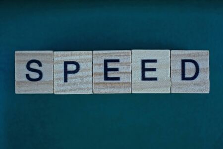 gray word speed made of small wooden letters on a green background