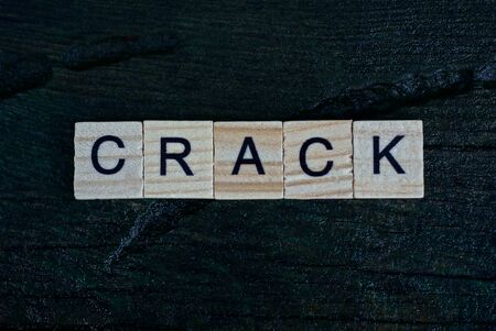gray word crack from small wooden letters on a black tableの写真素材