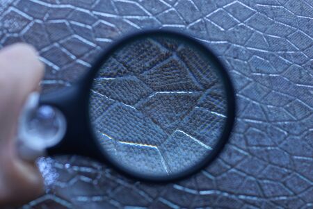 a large black magnifier in hand increases the gray pattern on the window glass