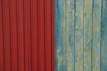 colored texture of red metal wall and frayed wooden boards in the fence