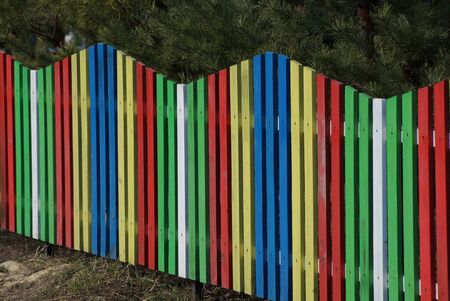 part of a colored wooden fence made of thin boards outside on a sunny dayの写真素材