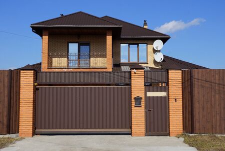 one large closed brown gate and part of the fence of bricks and metal in the wallの写真素材