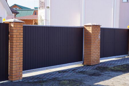 brown gate and part of the fence of bricks and metal in the wall on a city street