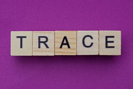 word trace from small gray wooden letters lies on a lilac backgroundの写真素材