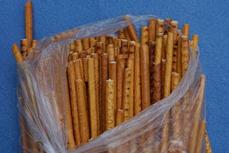food from dry brown straws in a torn gray plastic bag on a blue table