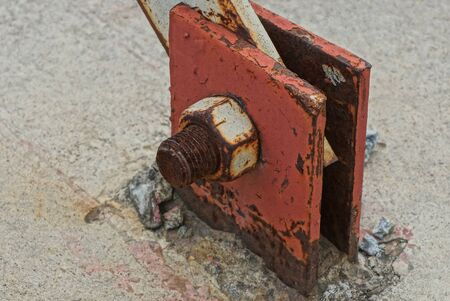 one brown rusty bolt with nut on a red iron plate in the streetの写真素材