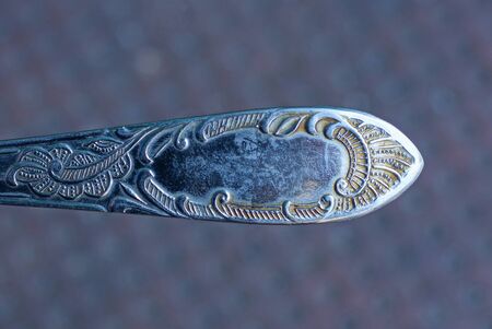 gray metal fork handle with a pattern on a brown background