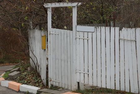 rural white fence from wooden boards and a closed door on the streetの写真素材