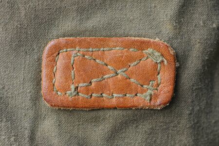 brown leather patch texture with stitches on green fabric