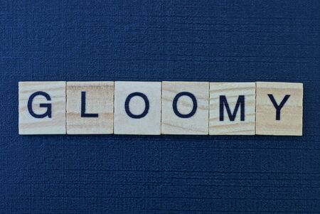 gray word gloomy of square wooden letters on a black dark tableの写真素材