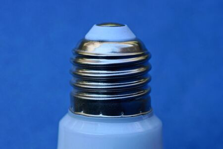 part of one white light bulb with a gray metal cap on a blue background