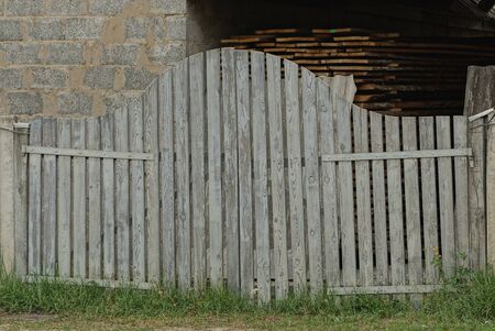 old white closed gate made of wooden boards on a rural street in green grassの写真素材