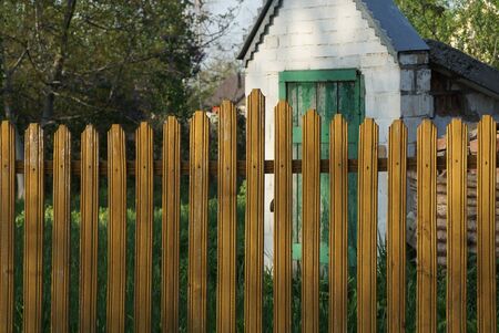 private long brown yellow fence from wooden boards on a rural streetの写真素材