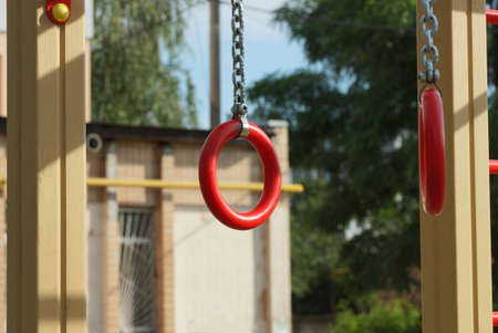 two red sports rings with gray iron chains on an outdoor sports ground