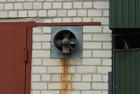one old gray iron fan on a white brick wall outsideの写真素材